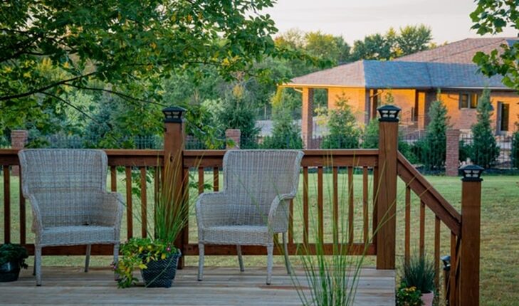 two straw chairs in front of a brown wooden fence